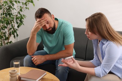 Photo of Betrayal. Wife showing smartphone with proofs to her unfaithful husband on sofa at home