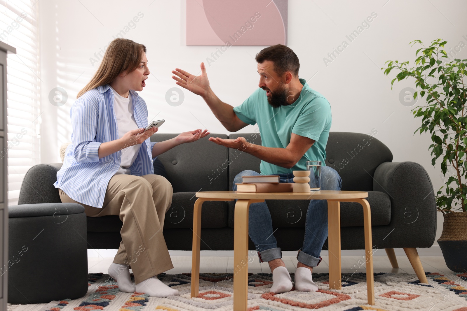 Betrayal. Emotional couple arguing on sofa at home Photo of Betrayal. Emotional couple arguing on sofa at home