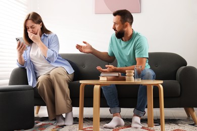 Photo of Betrayal. Emotional couple arguing on sofa at home