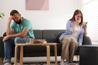 Photo of Betrayal. Jealous woman finding proofs of her unfaithful husband on smartphone on sofa at home