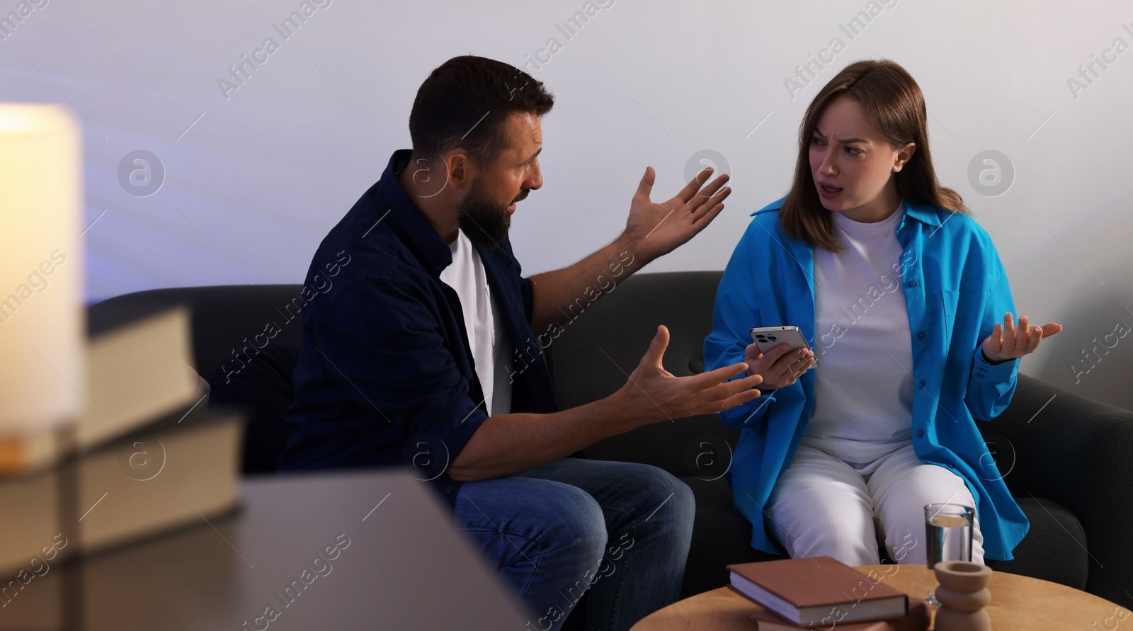 Betrayal. Emotional couple arguing on sofa at home Photo of Betrayal. Emotional couple arguing on sofa at home