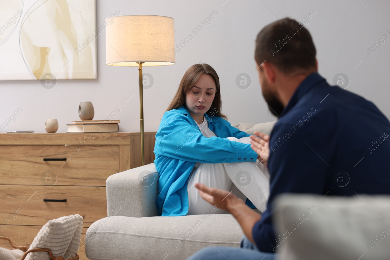 Photo of Betrayal. Man talking to his frustrated wife on sofa at home