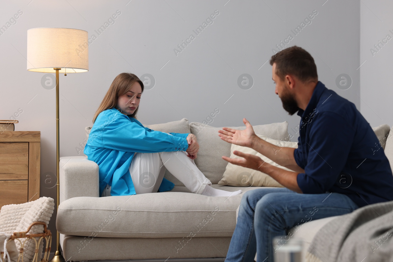 Photo of Betrayal. Man talking to his frustrated wife on sofa at home