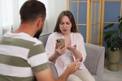 Photo of Betrayal. Jealous woman finding proofs of her unfaithful husband on armchair at home
