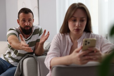 Photo of Betrayal. Jealous woman finding proofs of her unfaithful husband on armchair at home, selective focus