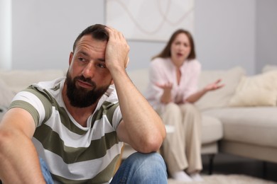 Photo of Betrayal. Angry woman shouting at her offended husband on sofa at home, selective focus