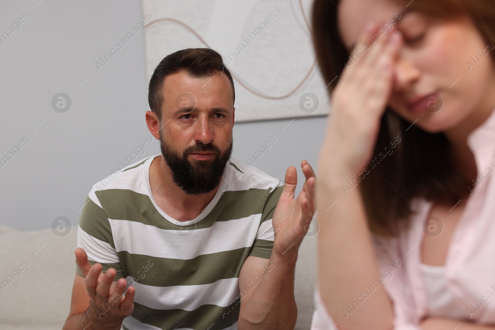 Photo of Betrayal. Man talking to his frustrated wife at home, selective focus