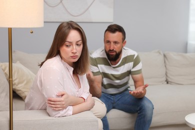 Photo of Betrayal. Man talking to his frustrated wife on sofa at home