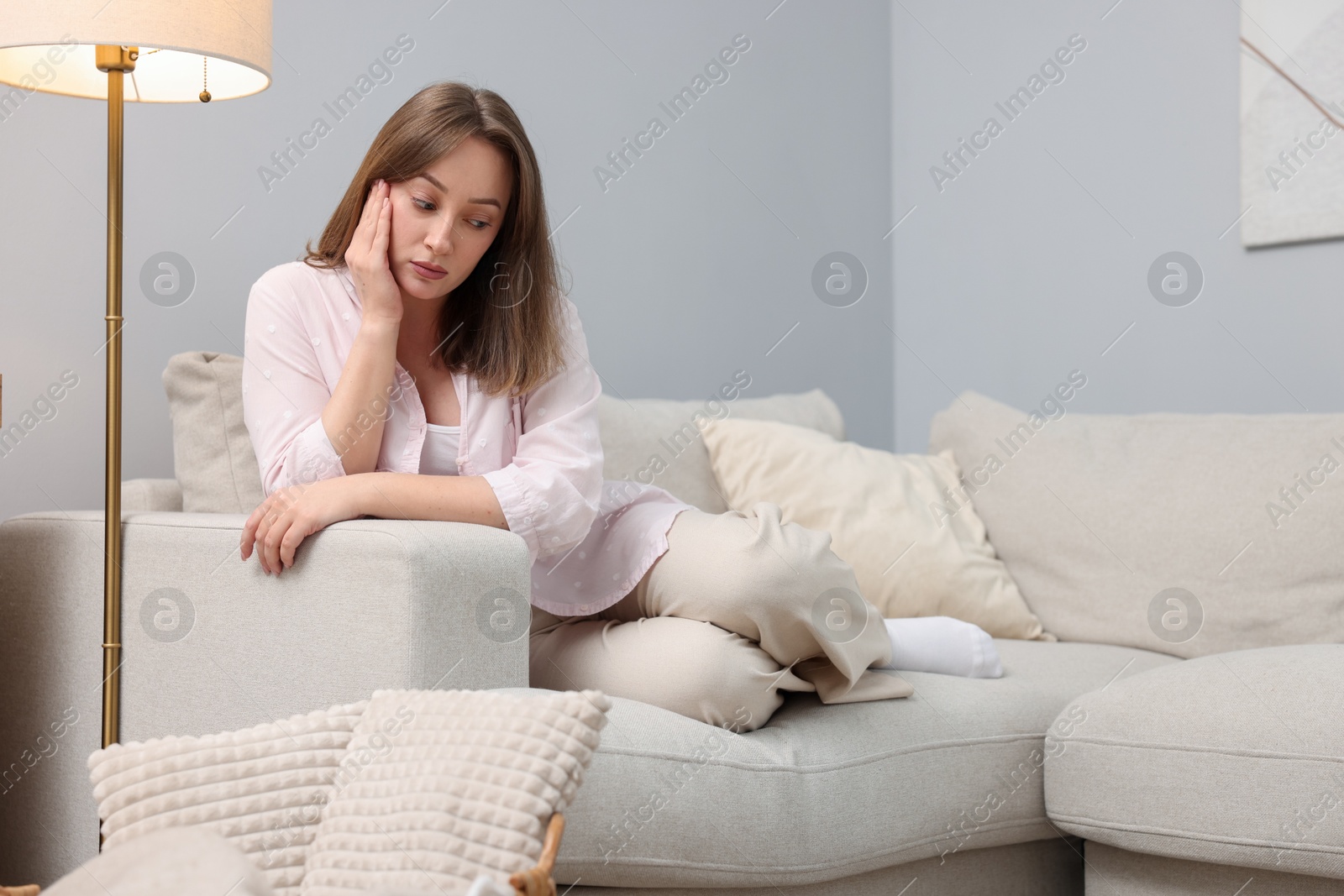 Photo of Betrayal. Lonely frustrated woman on sofa at home
