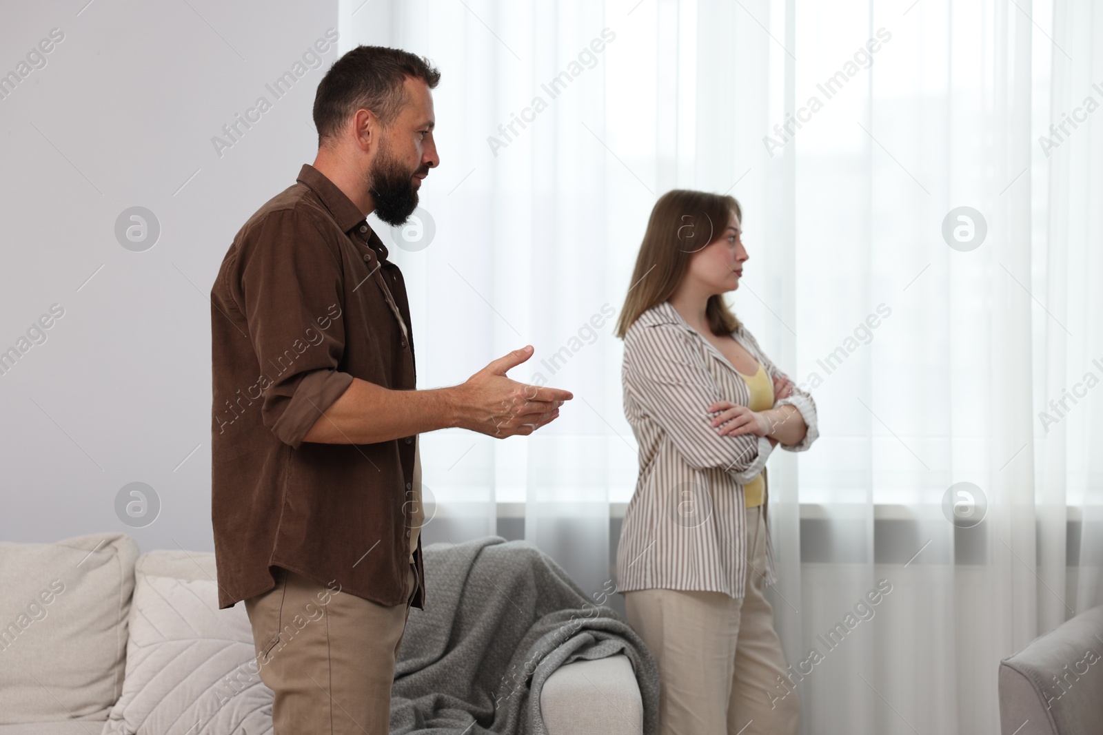 Photo of Betrayal. Man talking to his offended wife at home