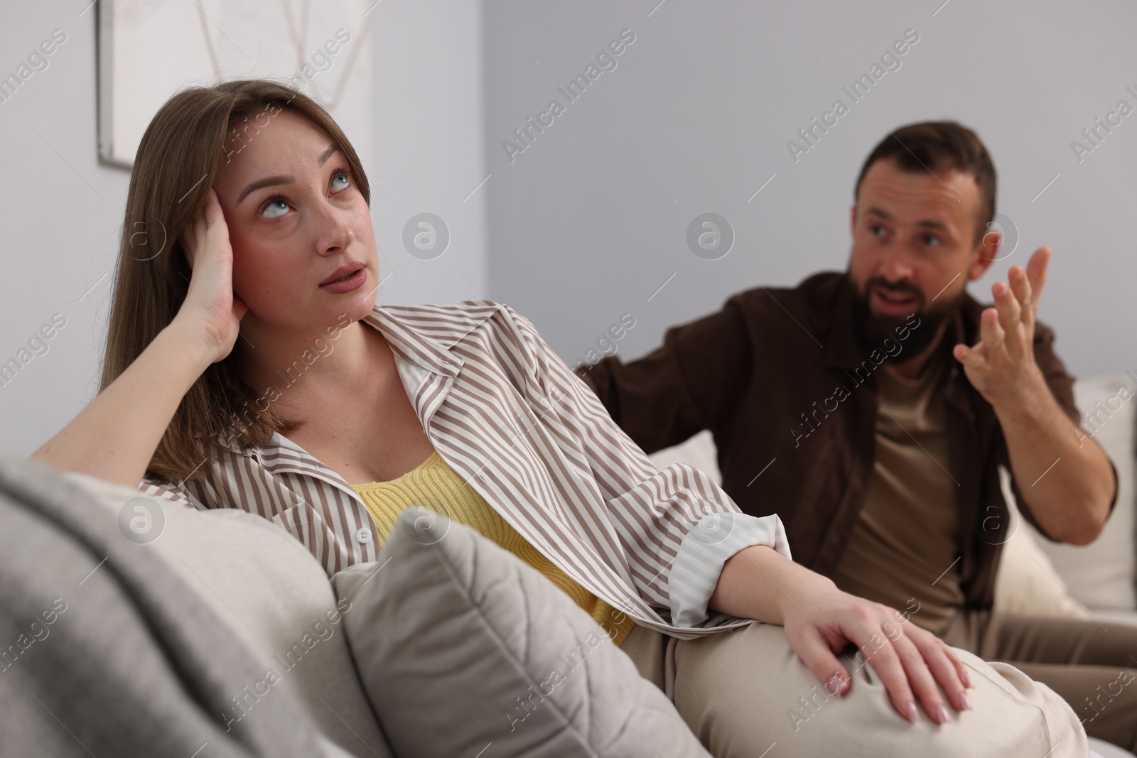 Betrayal. Man talking to his offended wife on sofa at home, selective focus Photo of Betrayal. Man talking to his offended wife on sofa at home, selective focus