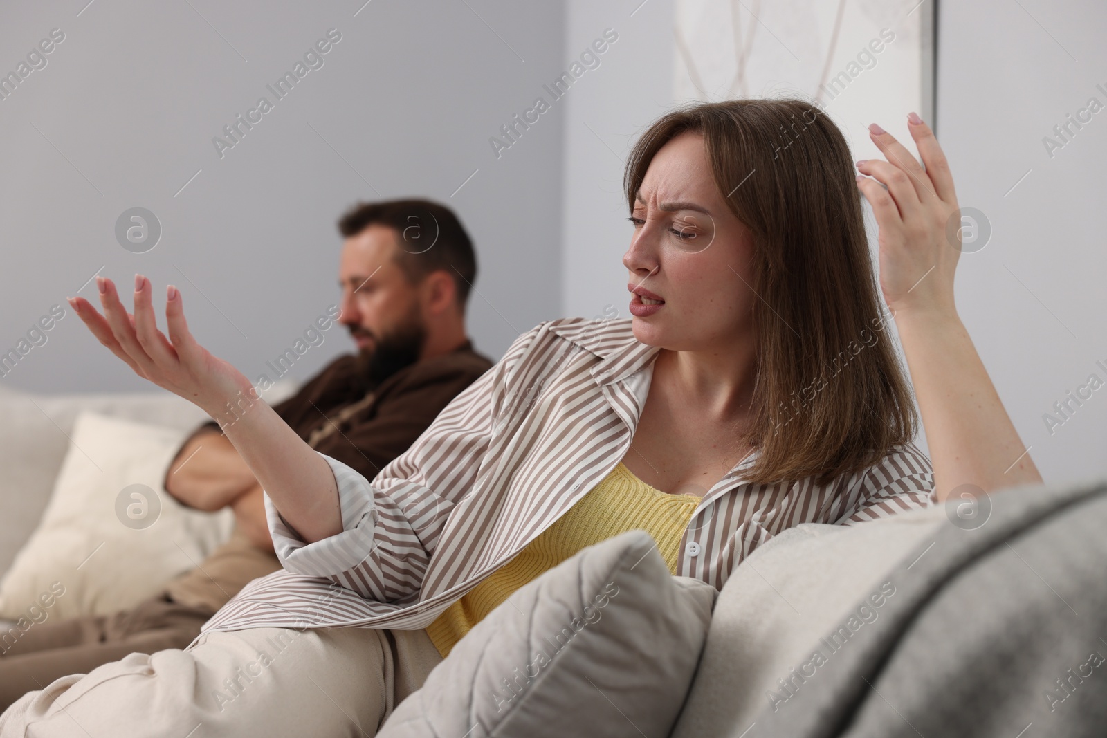 Photo of Betrayal. Emotional woman talking to her husband on sofa at home