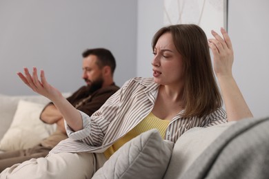 Photo of Betrayal. Emotional woman talking to her husband on sofa at home
