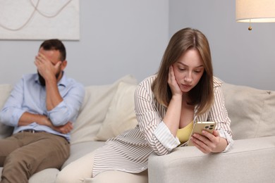 Photo of Betrayal. Jealous woman finding proofs of her unfaithful husband on smartphone on sofa at home