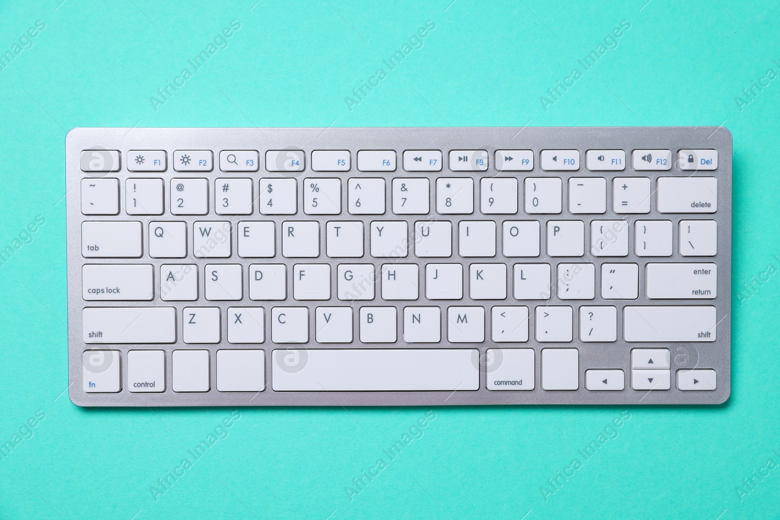 Photo of Modern wireless computer keyboard on turquoise background, top view