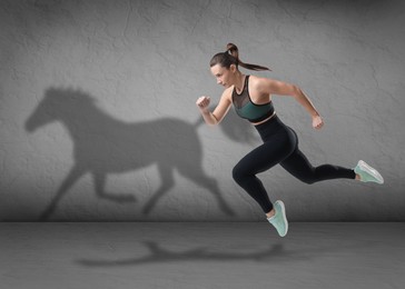 Image of Athletic young woman running. Her shadow in form of horse on brick wall. Sports poster