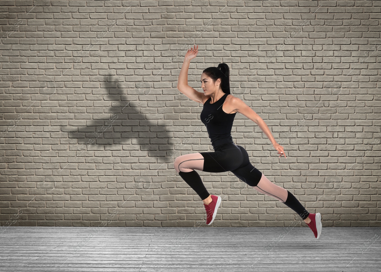 Athletic young woman running. Her shadow in form of hawk on brick wall. Sports poster Image of Athletic young woman running. Her shadow in form of hawk on brick wall. Sports poster