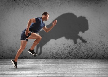 Image of Athletic man running. His shadow in form of ox on grey wall. Sports poster