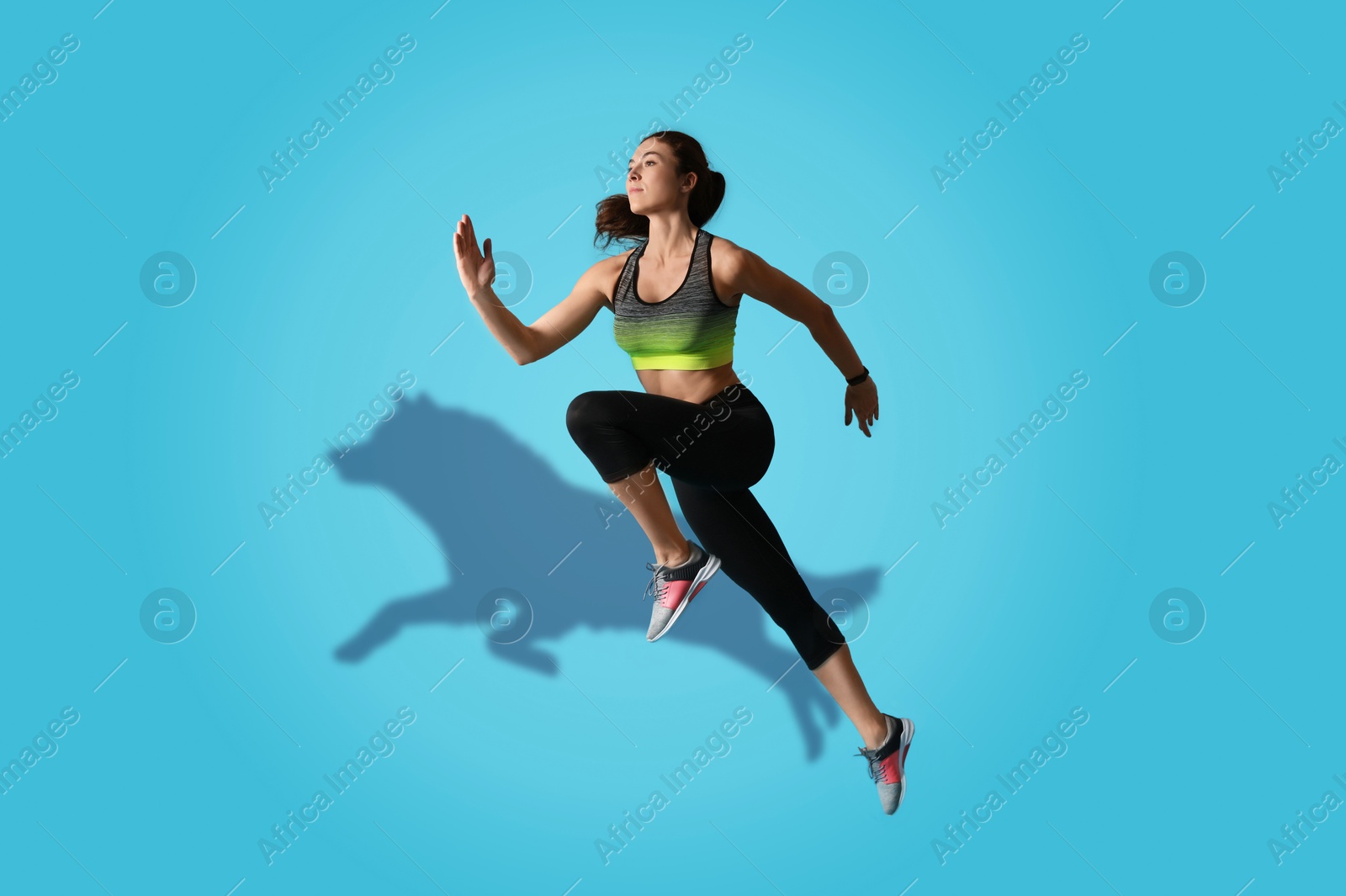 Athletic young woman running. Her shadow in form of hound on light blue background. Sports poster Image of Athletic young woman running. Her shadow in form of hound on light blue background. Sports poster