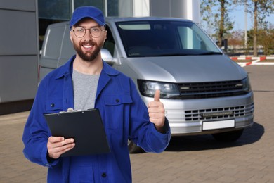 Image of Car service worker with clipboard and vehicle outdoors
