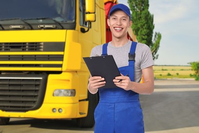 Image of Car service worker with clipboard and truck outdoors