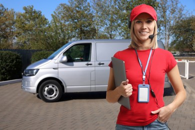 Image of Car service worker with headset and clipboard against vehicle outdoors. Client support