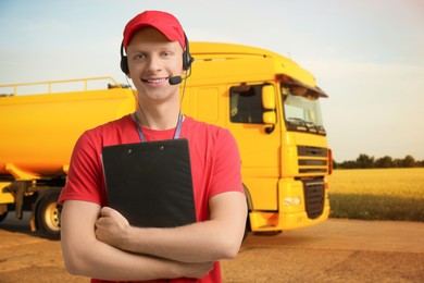 Image of Car service worker with headset and clipboard against truck outdoors. Client support