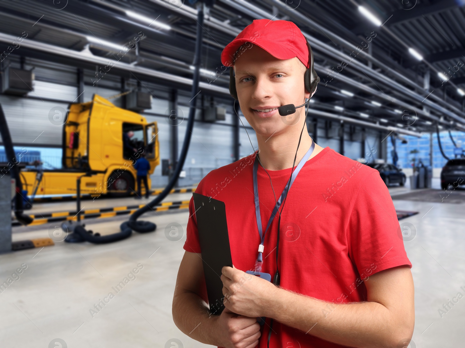 Image of Car service worker with headset and clipboard against truck at station. Client support