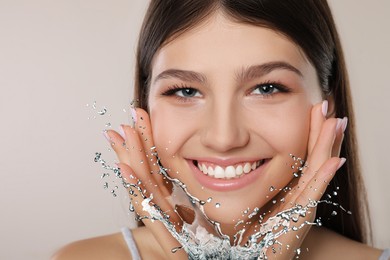 Image of Young girl with smooth skin and water splash against light grey background