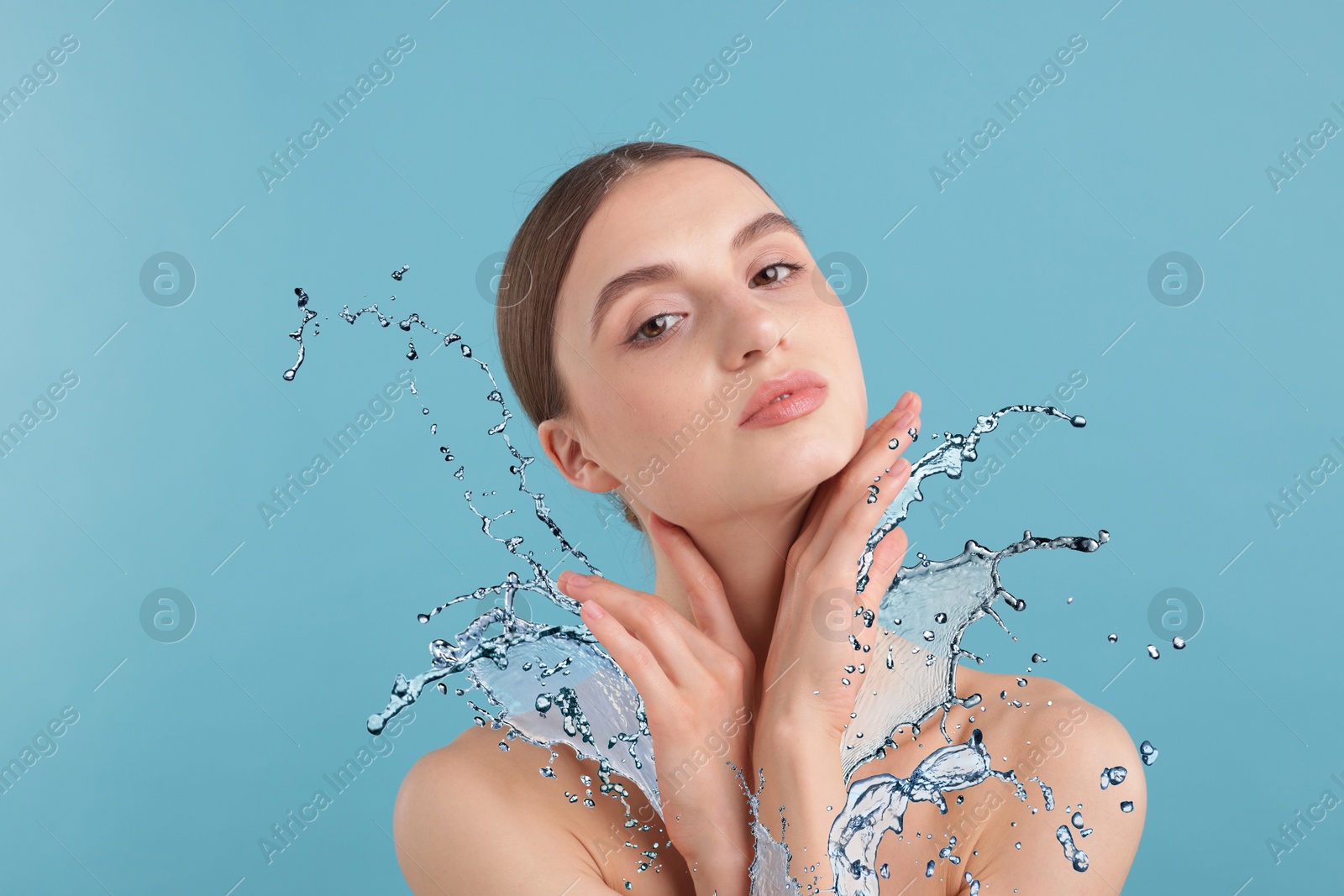 Woman with smooth skin and water splash against light blue background Image of Woman with smooth skin and water splash against light blue background