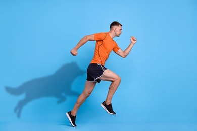 Image of Athletic man running. His shadow in form of hound on light blue background. Sports poster