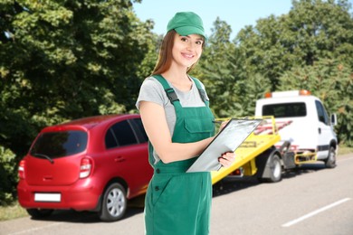 Image of Car service worker with clipboard near red auto and tow truck outdoors