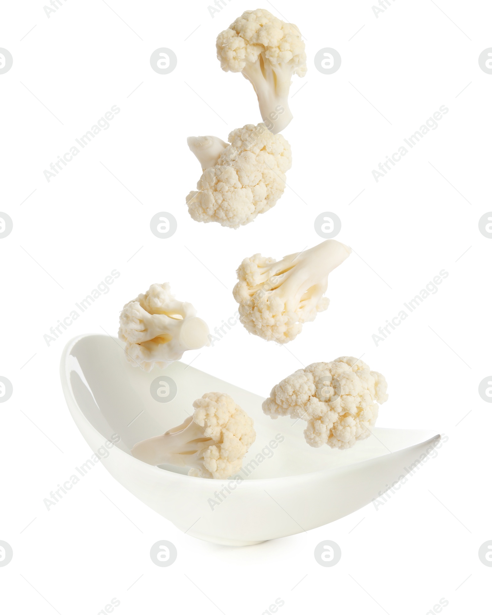 Image of Cauliflower florets falling into bowl against white background