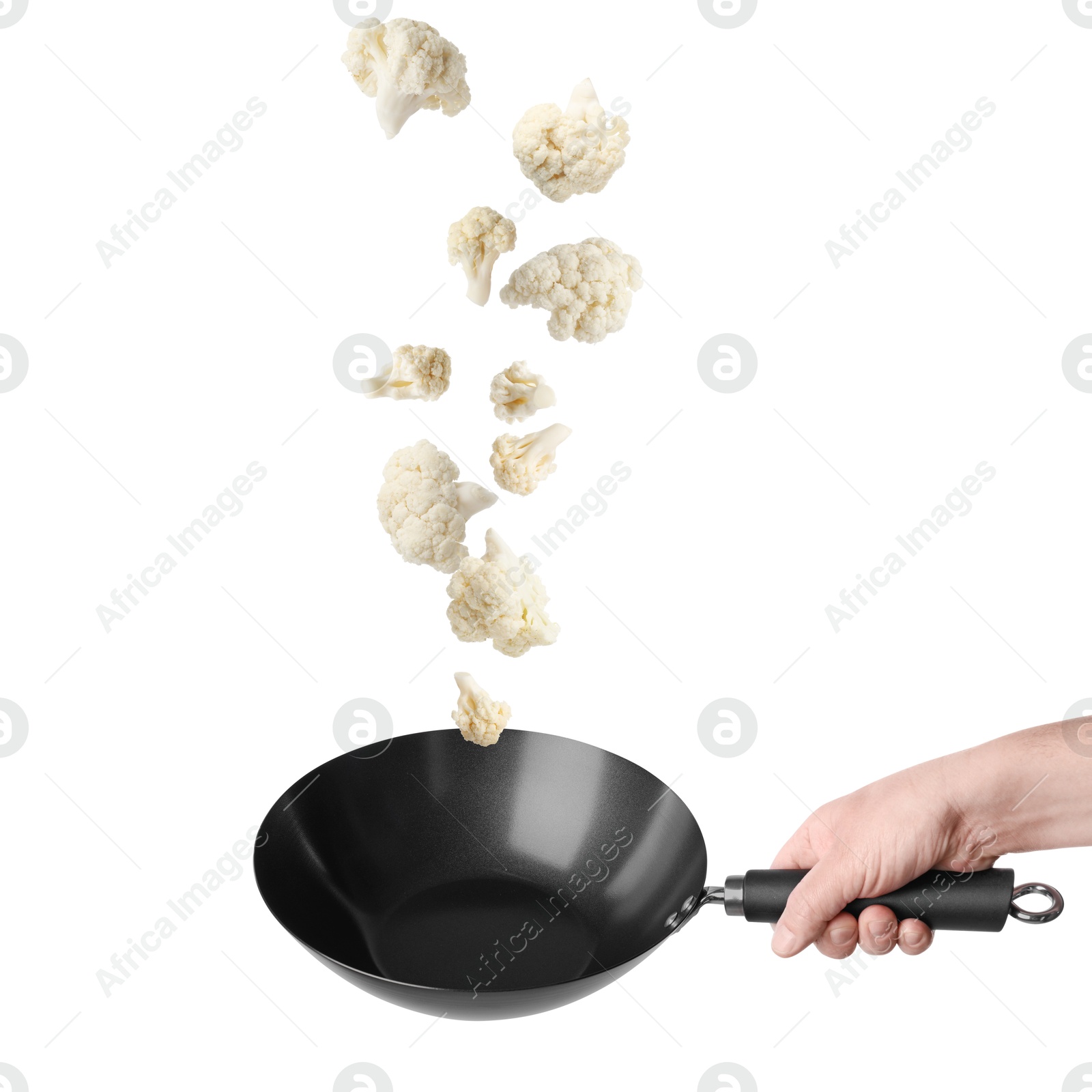 Man tossing cauliflower while frying it in wok against white background, closeup Image of Man tossing cauliflower while frying it in wok against white background, closeup