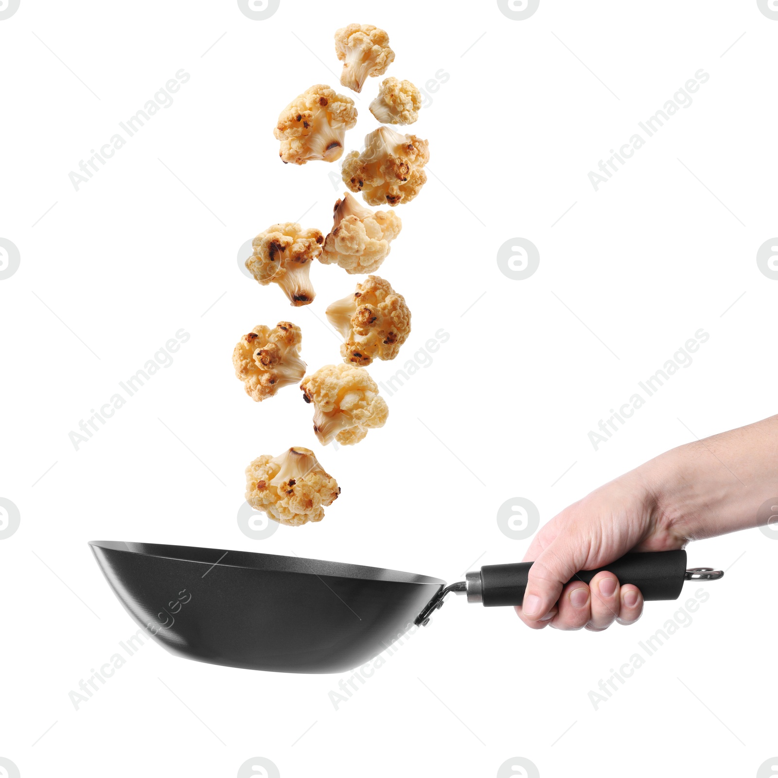 Man tossing cauliflower while frying it in wok against white background, closeup Image of Man tossing cauliflower while frying it in wok against white background, closeup
