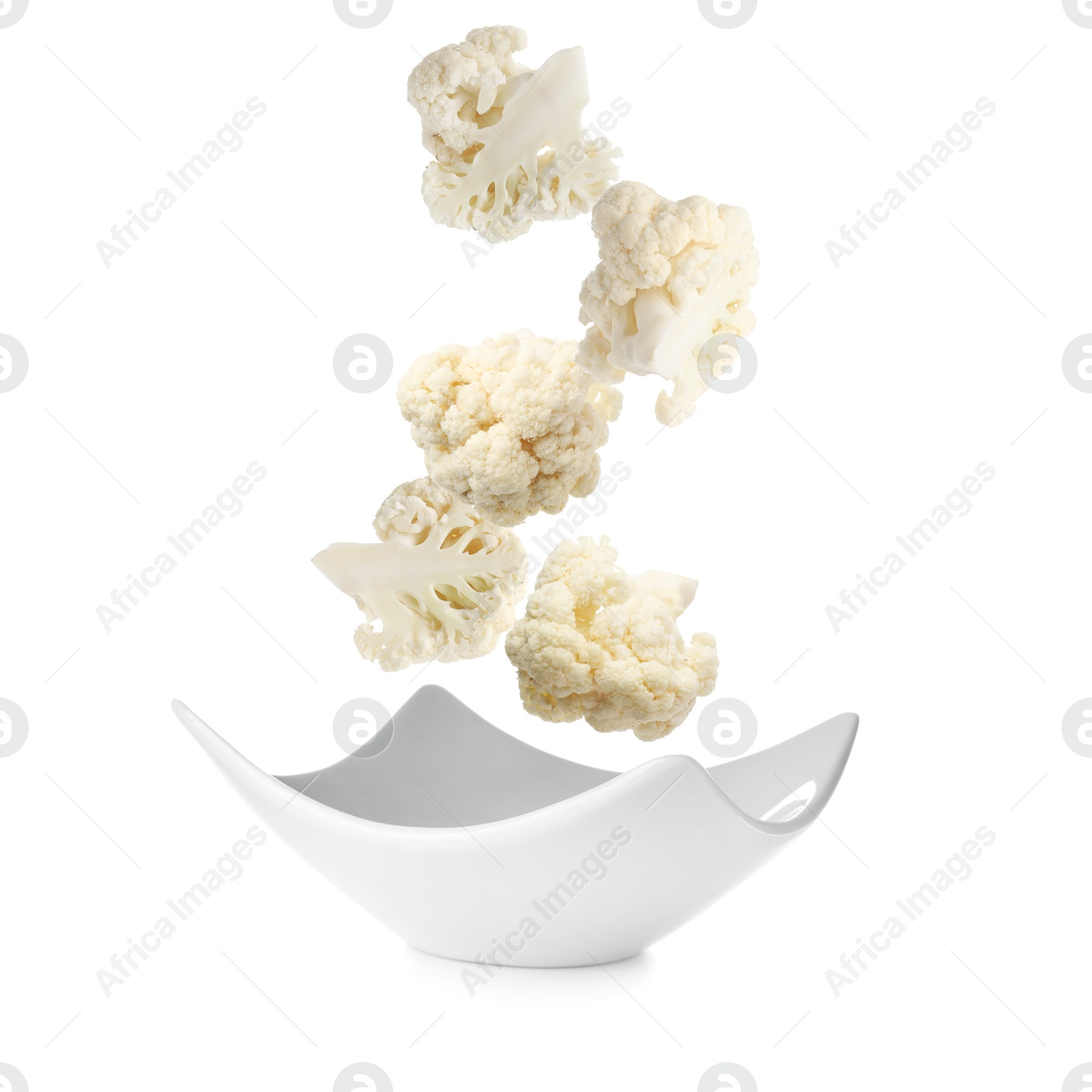 Image of Cauliflower florets falling into bowl against white background