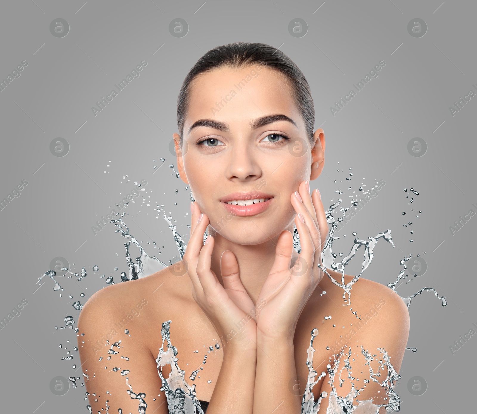 Woman with smooth skin and water splash against grey background Image of Woman with smooth skin and water splash against grey background