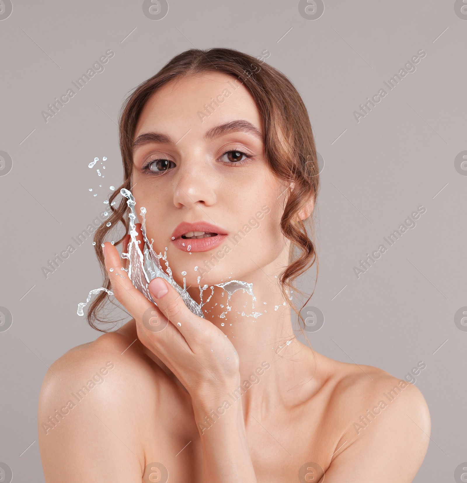 Woman with smooth skin and water splash against grey background Image of Woman with smooth skin and water splash against grey background
