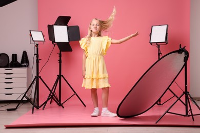 Photo of Little girl on pink background in photo studio with professional equipment