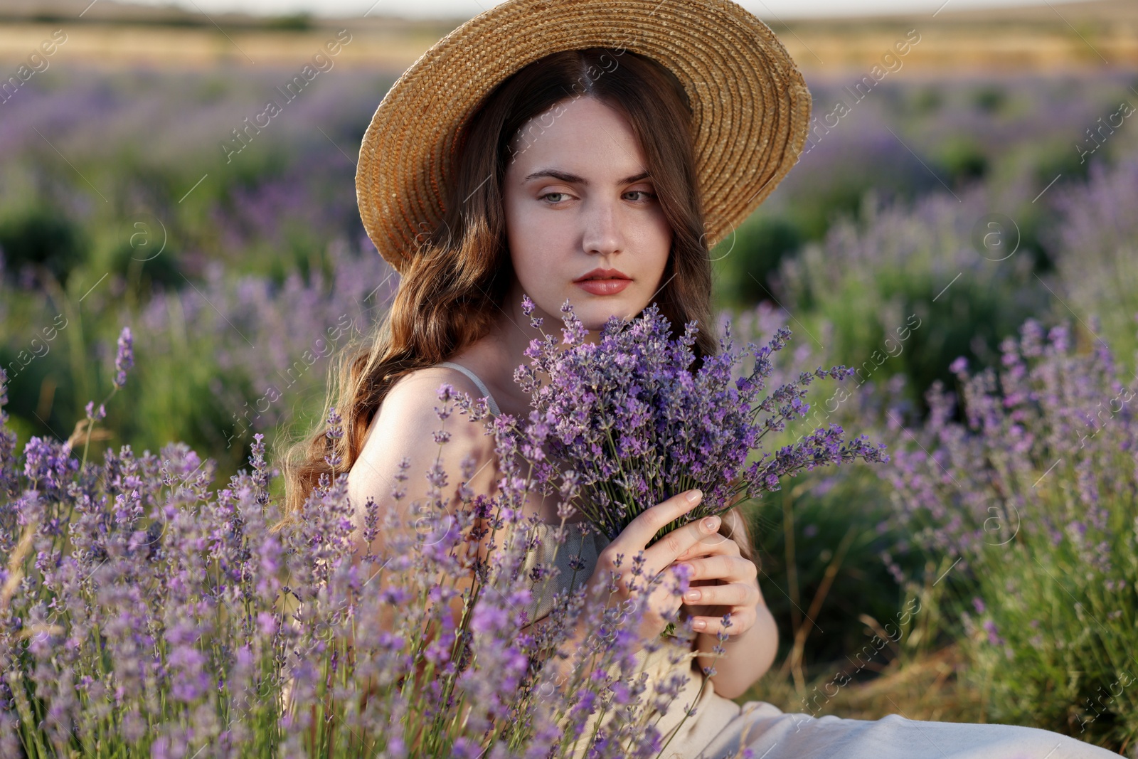 Beautiful young woman with lavender flowers in field Photo of Beautiful young woman with lavender flowers in field