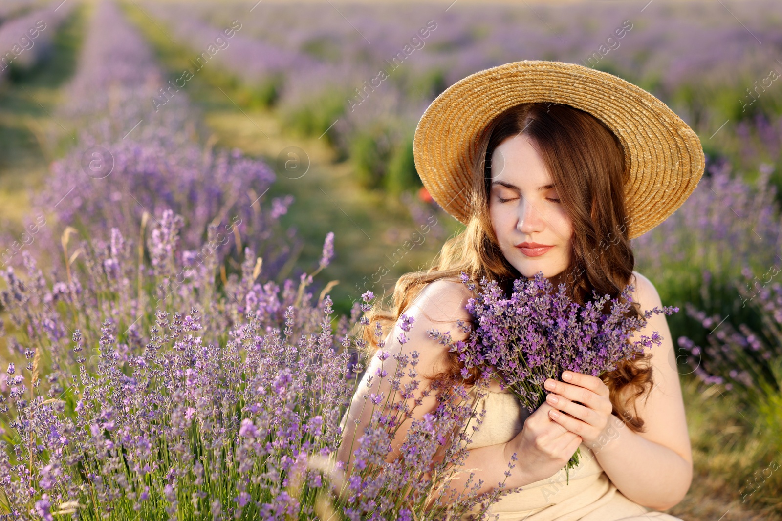Beautiful young woman with lavender flowers in field Photo of Beautiful young woman with lavender flowers in field