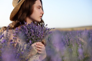 Photo of Beautiful young woman with lavender flowers in field. Space for text