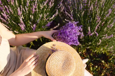 Photo of Woman with beautiful lavender flowers and straw hat in field, top view