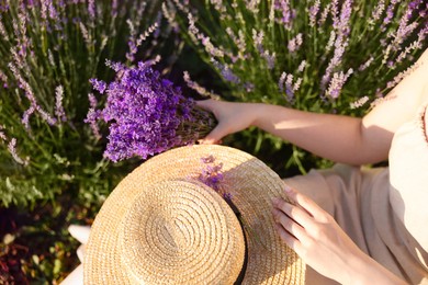 Photo of Woman with beautiful lavender flowers and straw hat in field, top view