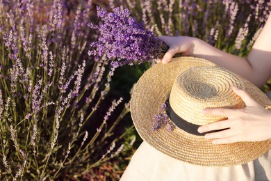 Photo of Woman with beautiful lavender flowers and straw hat in field, closeup
