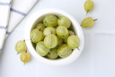 Photo of Fresh green gooseberries in bowl on white table, top view
