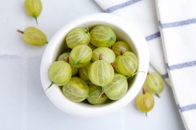 Photo of Fresh green gooseberries in bowl on white table, top view