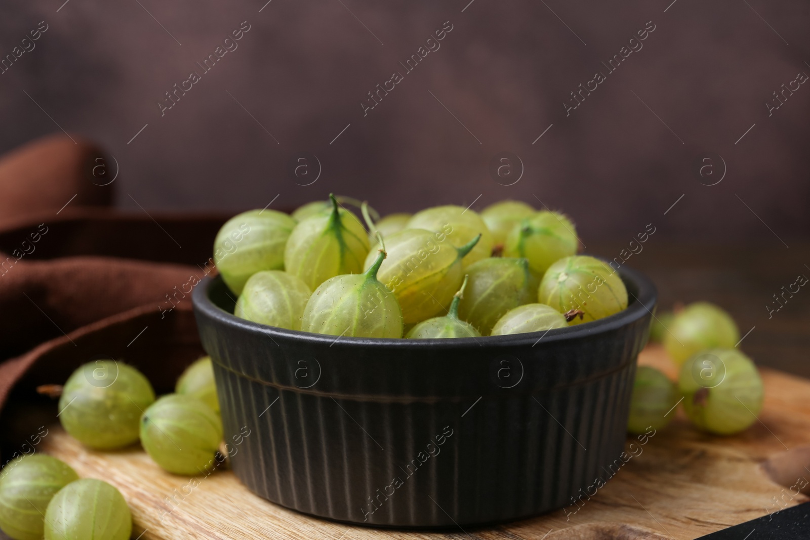 Photo of Fresh green gooseberries in bowl on table, closeup
