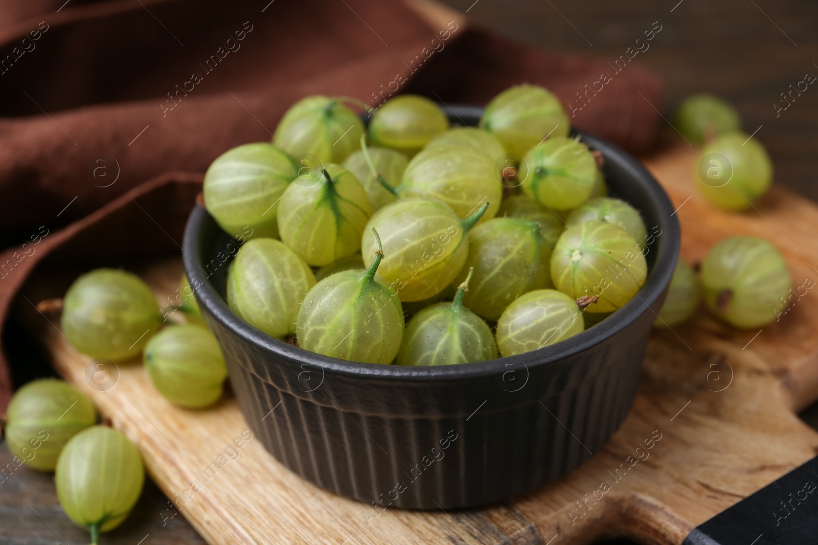 Photo of Fresh green gooseberries in bowl on table, closeup