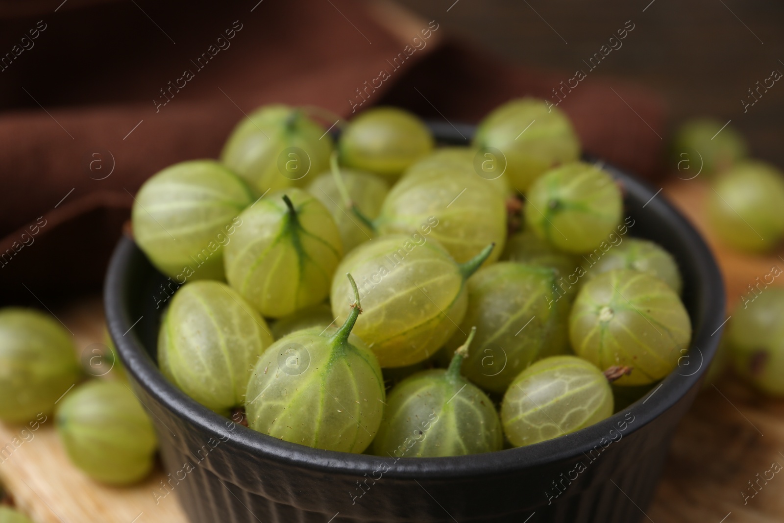 Photo of Fresh green gooseberries in bowl on table, closeup